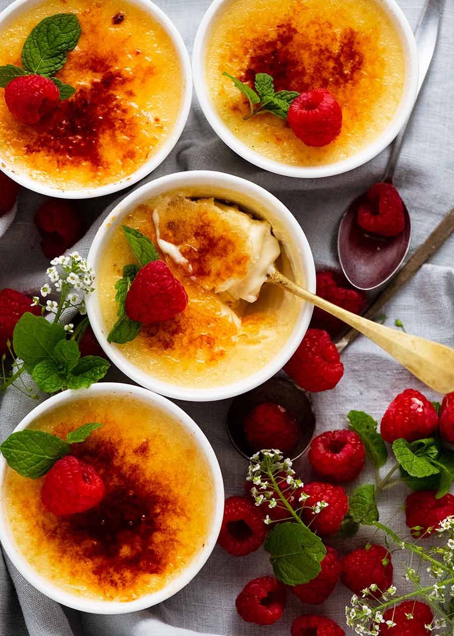 Overhead photo of Creme Br&ucirc;l&eacute;e decorated with raspberries and mint