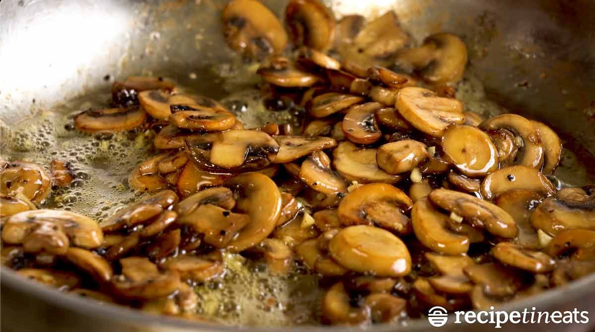 Buttery garlic saut&eacute;ed mushrooms in a skillet
