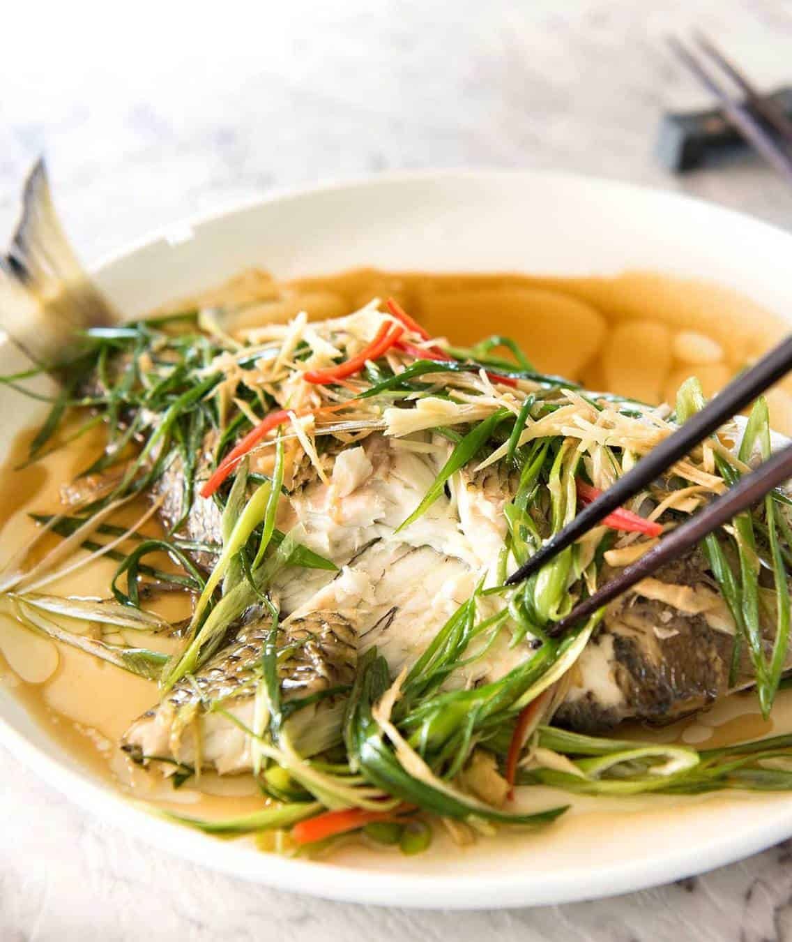 A Chinese Steamed Fish topped with Ginger and Shallots and seasonings, with hot oil poured over it to create a dramatic sizzle and an amazing sauce. So simple, yet so utterly delicious. Steam OR bake the fish! dev.recipetineats.com