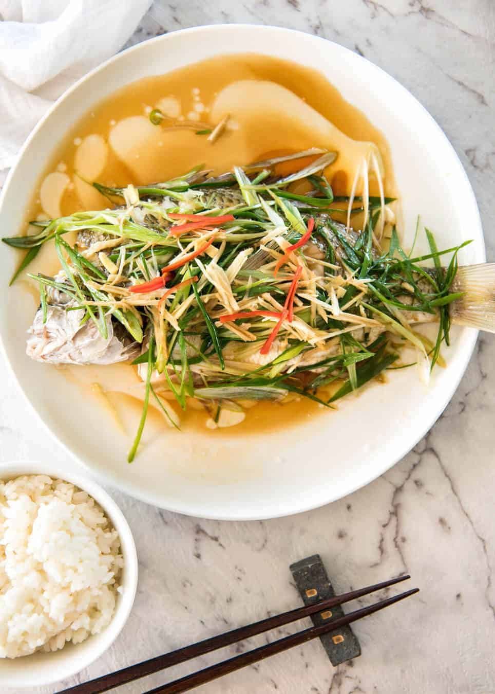 A Chinese Steamed Fish topped with Ginger and Shallots and seasonings, with hot oil poured over it to create a dramatic sizzle and an amazing sauce. So simple, yet so utterly delicious. Steam OR bake the fish! dev.recipetineats.com