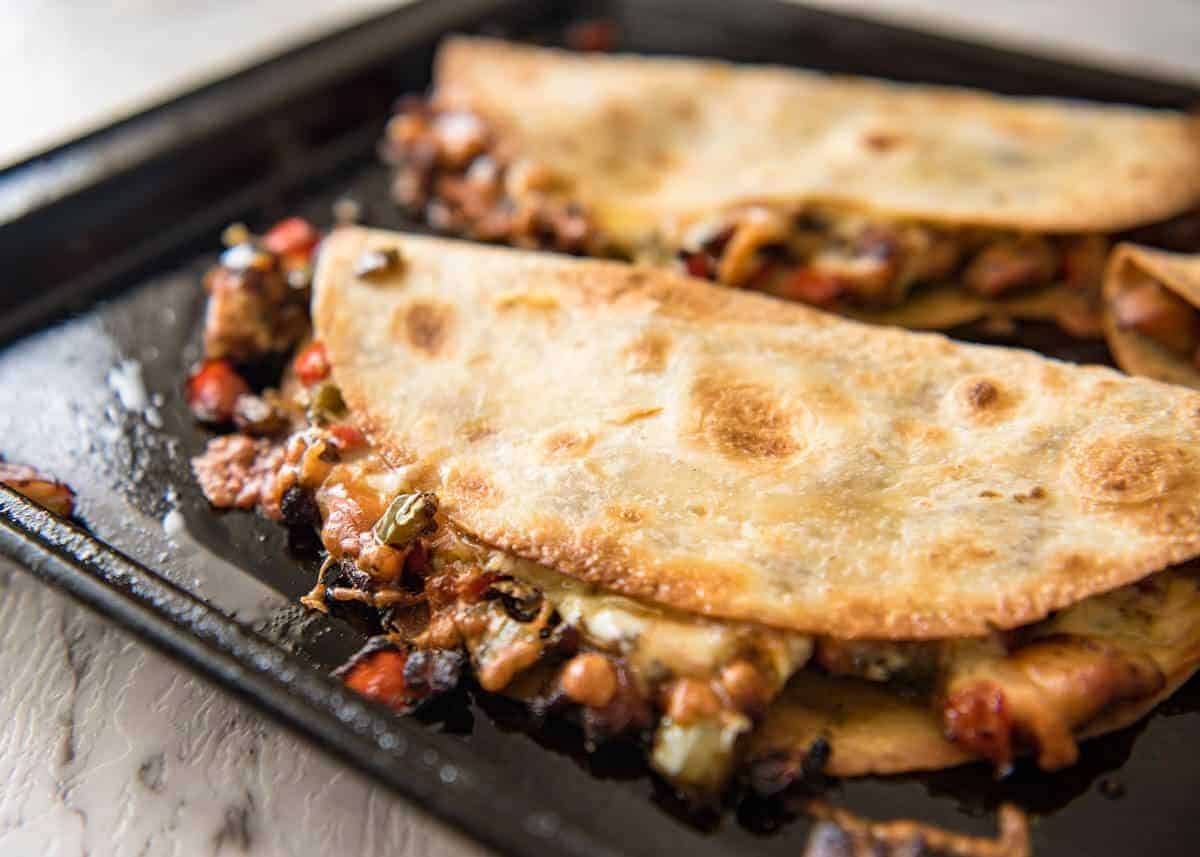 Crispy Oven Baked Chicken Quesadillas - This is how to make multiple Quesadillas at the same time! Crispy on the outside, stuffed with Mexican seasoned chicken and capsicum / bell peppers (and cheese of course!) dev.recipetineats.com