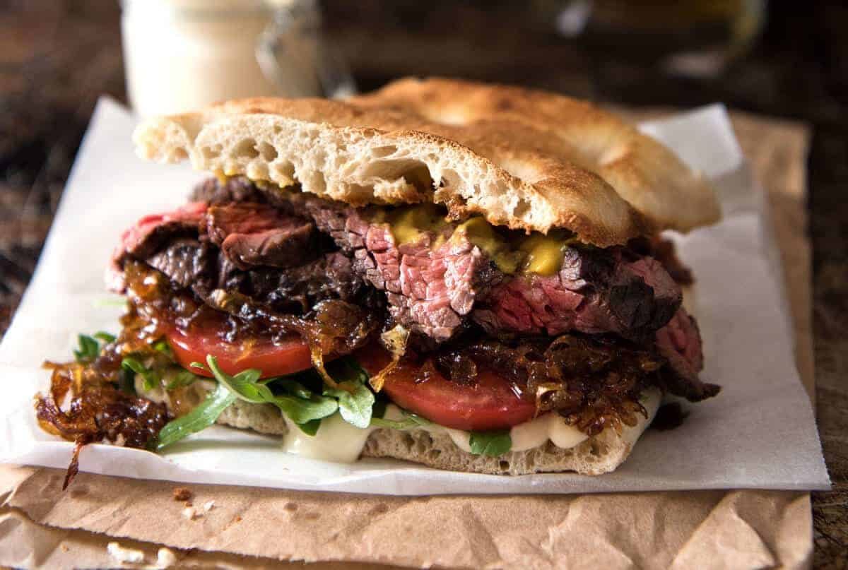 A juicy Steak Sandwich loaded with tender slices of steak, caramelised onion, garlic aioli, lettuce, tomato and mustard. dev.recipetineats.com