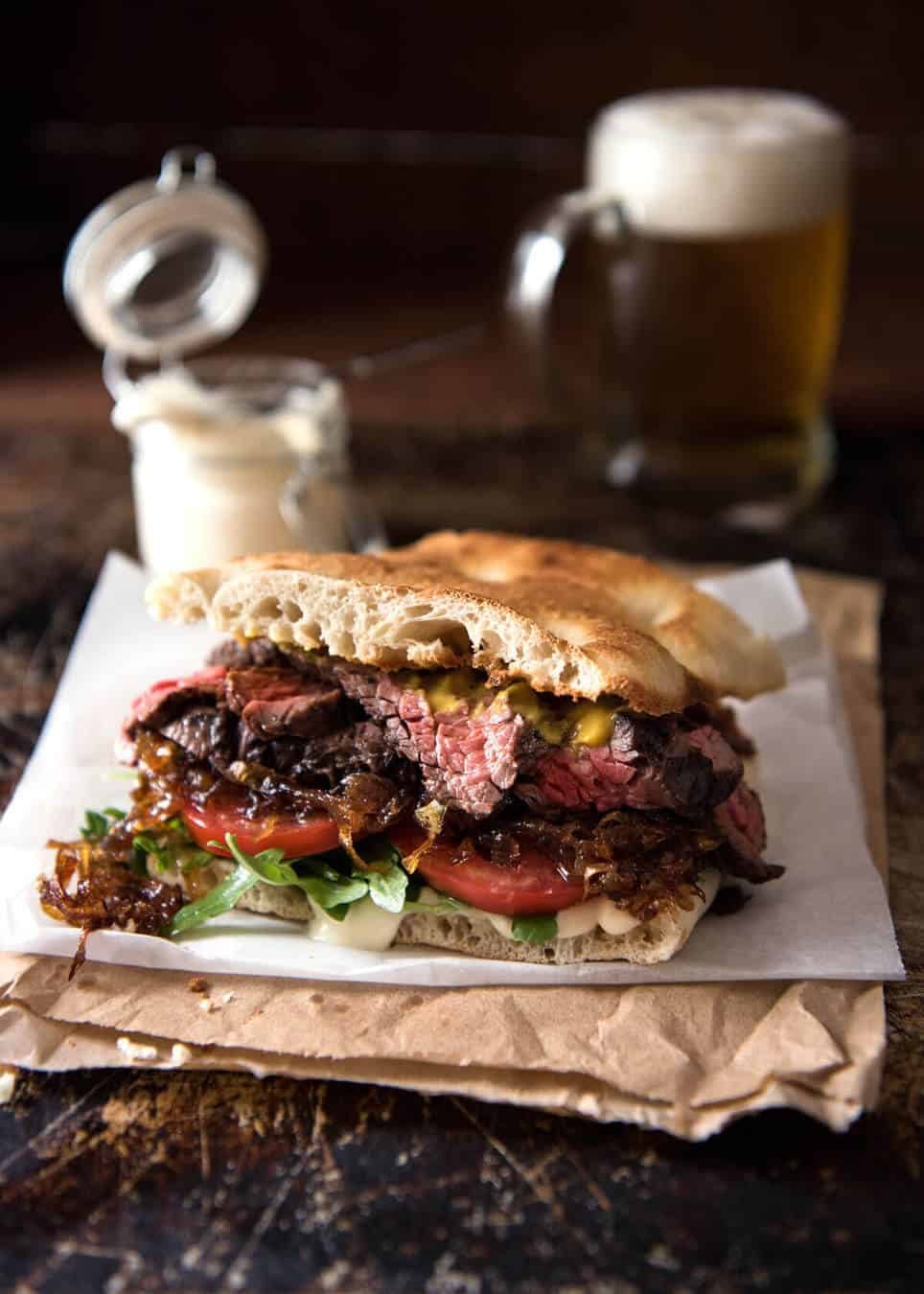 A juicy Steak Sandwich loaded with tender slices of steak, caramelised onion, garlic aioli, lettuce, tomato and mustard. dev.recipetineats.com