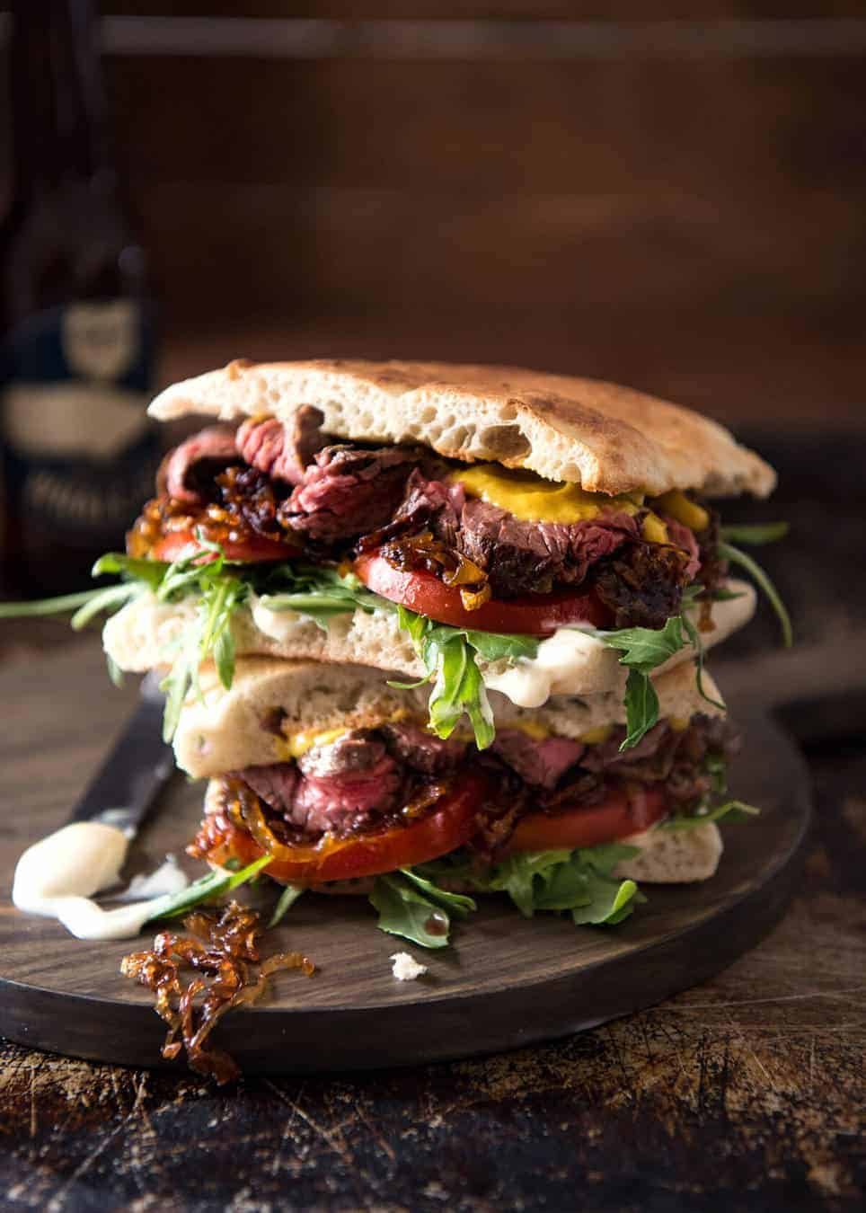 A juicy Steak Sandwich loaded with tender slices of steak, caramelised onion, garlic aioli, lettuce, tomato and mustard. dev.recipetineats.com