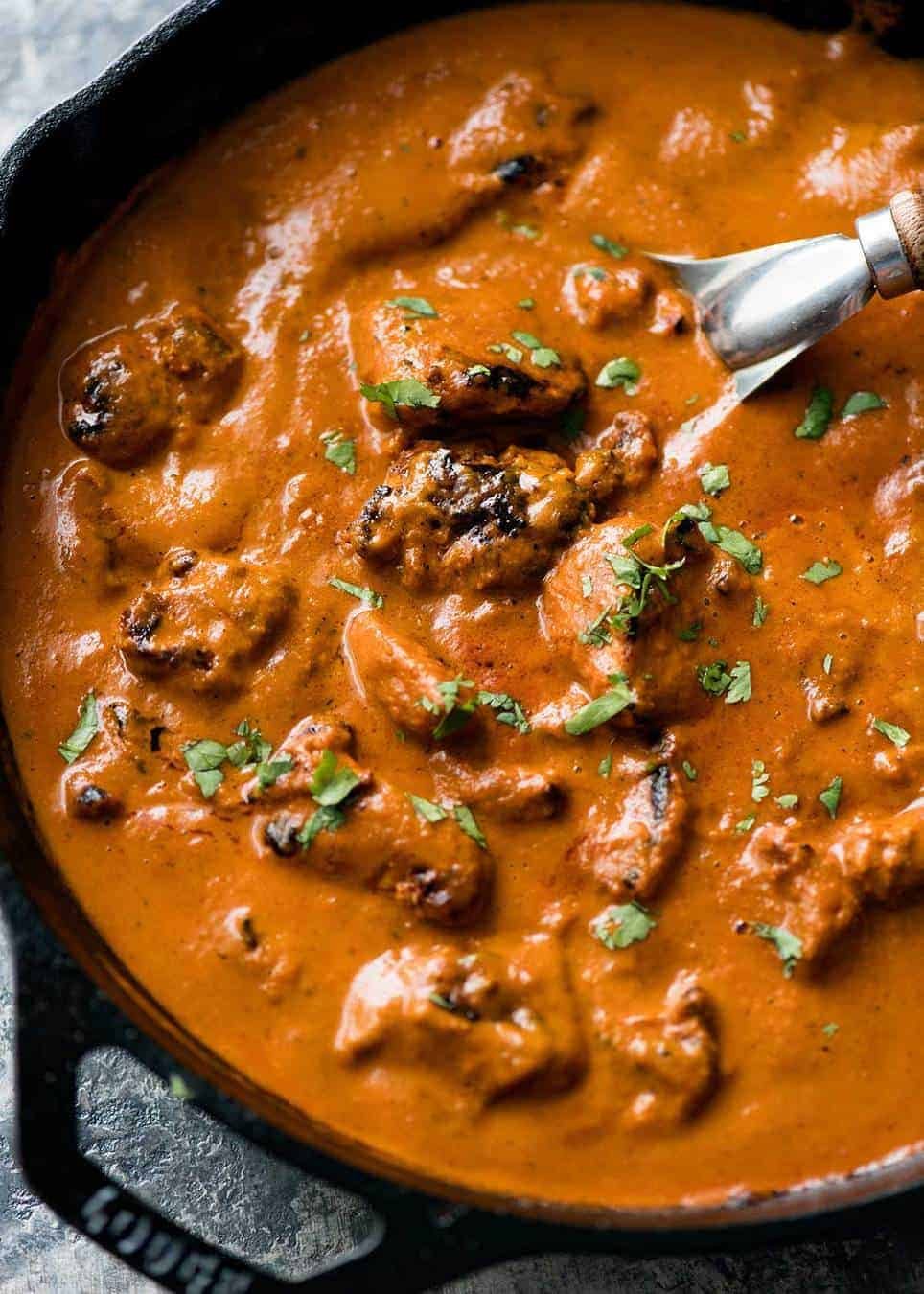 Chicken Tikka Masala in a black skillet garnished with coriander / cilantro.