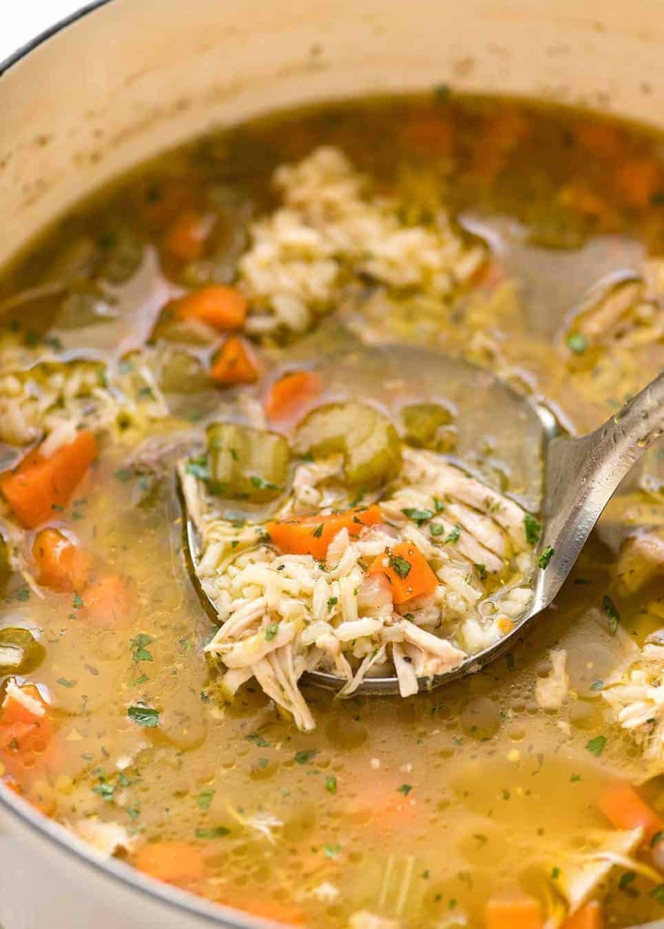 Easy Chicken and Rice Soup being scooped out of a white pot.