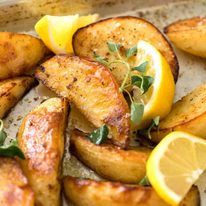 Close up of Greek Lemon Potatoes on a roasting tray, fresh out of the oven