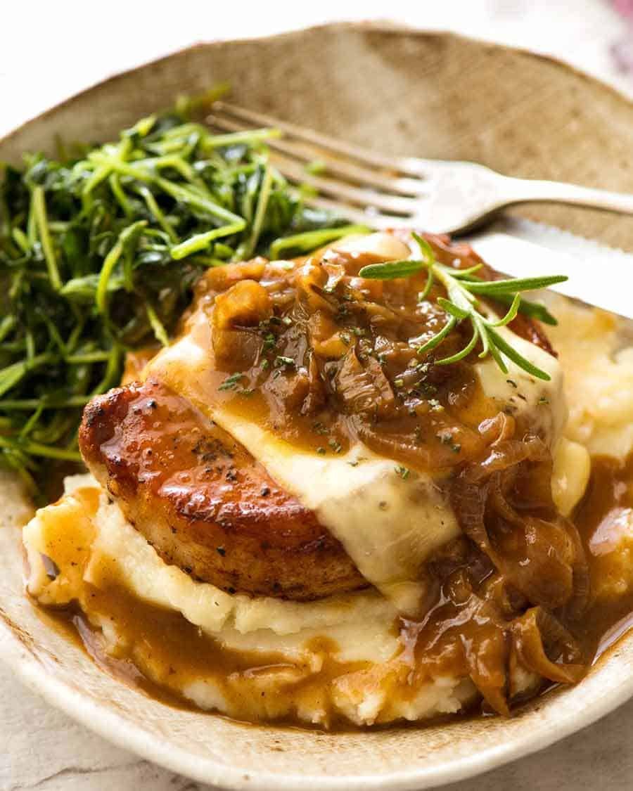 French Onion Smothered Pork Chops on mashed potato with a side of saut&eacute;ed snow pea sprouts