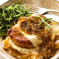 French Onion Smothered Pork Chops on mashed potato with a side of saut&eacute;ed snow pea sprouts
