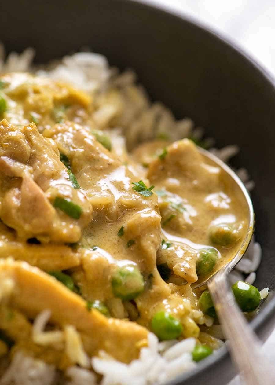 Close up of easy Chicken Curry served over rice in a rustic black bowl.