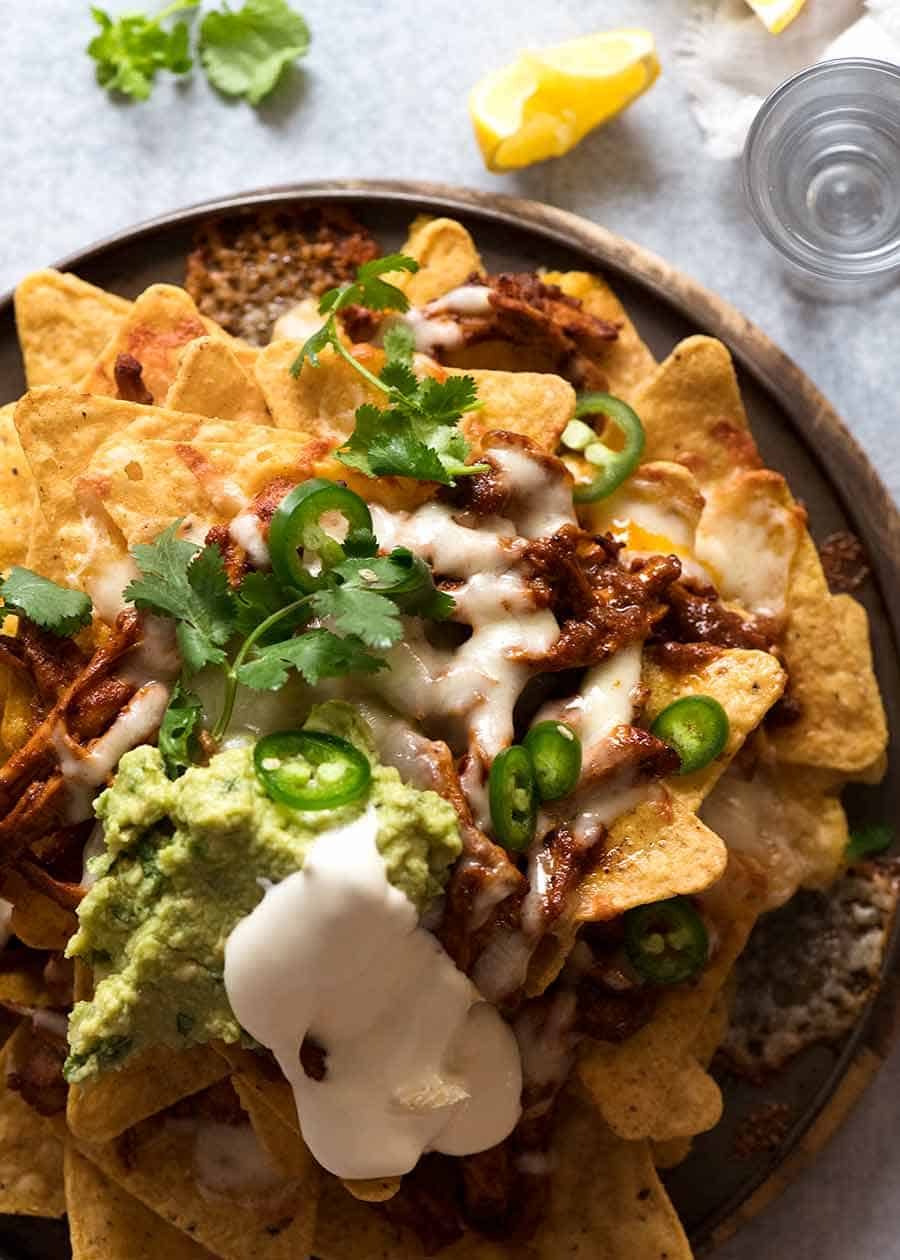 Overhead photo of Chicken Nachos with toppings - sour cream, jalape&ntilde;o guacamole, coriander / cilantro