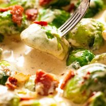 Fork picking up saut&eacute;ed Brussels sprouts in a creamy sauce