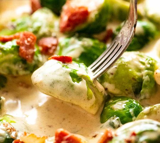 Fork picking up saut&eacute;ed Brussels sprouts in a creamy sauce