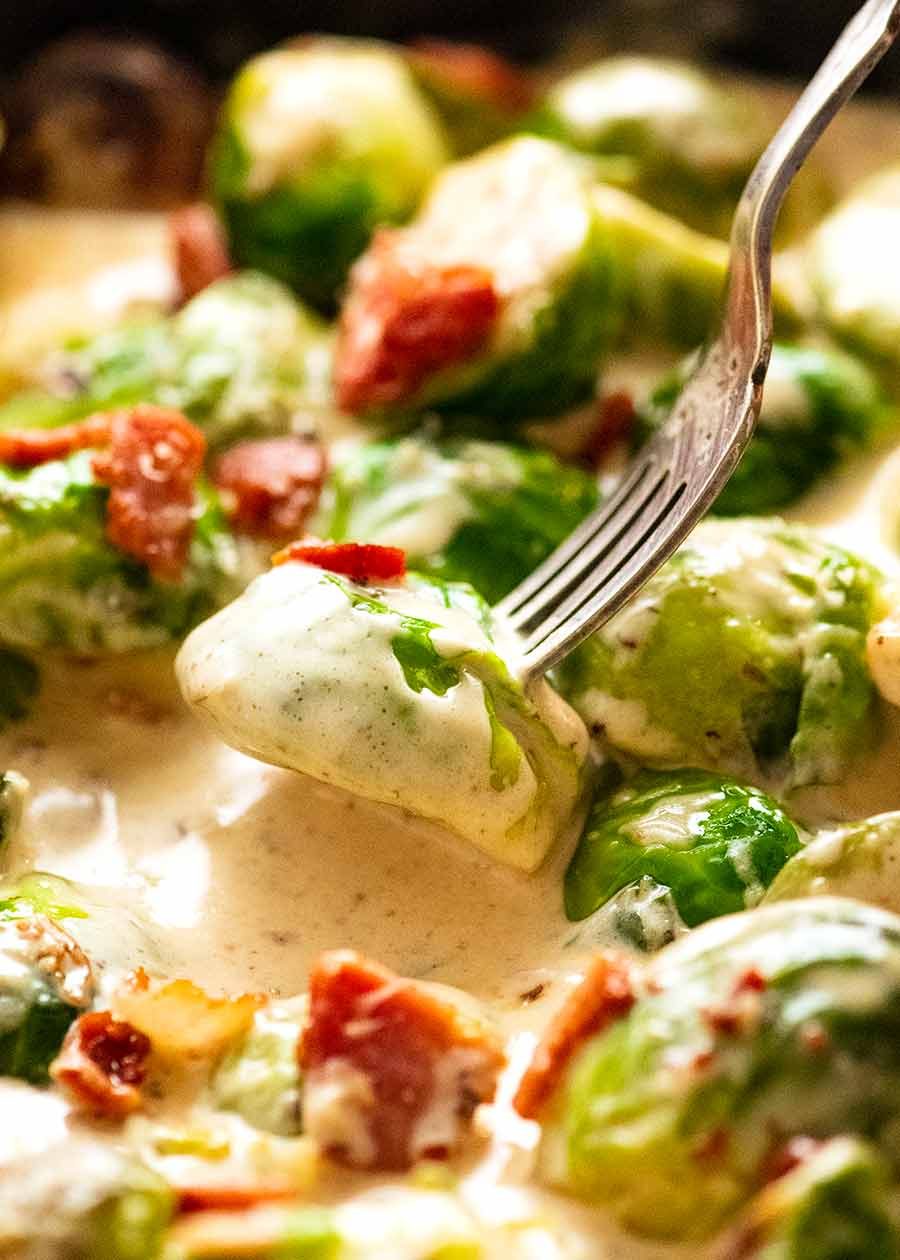 Fork picking up saut&eacute;ed Brussels sprouts in a creamy sauce