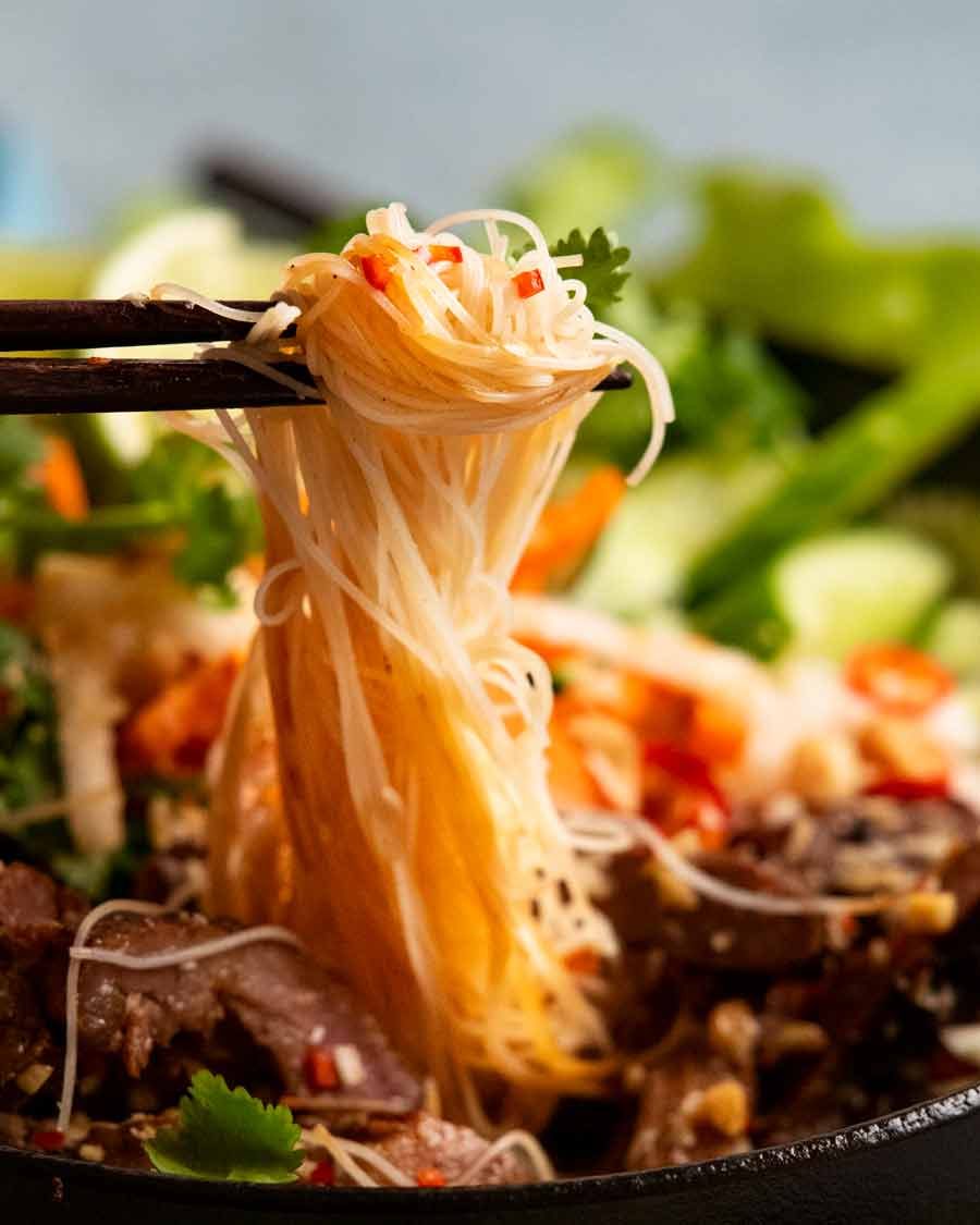 Chopsticks picking up noodles from Vietnamese noodles with lemongrass pork (B&uacute;n thịt nướng) noodle bowl